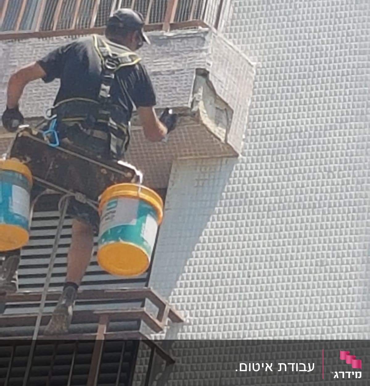 אדם מבצע איטום על קיר חיצוני עם דלי צבע